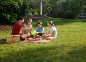 Caucasian family of four having picnic in park.